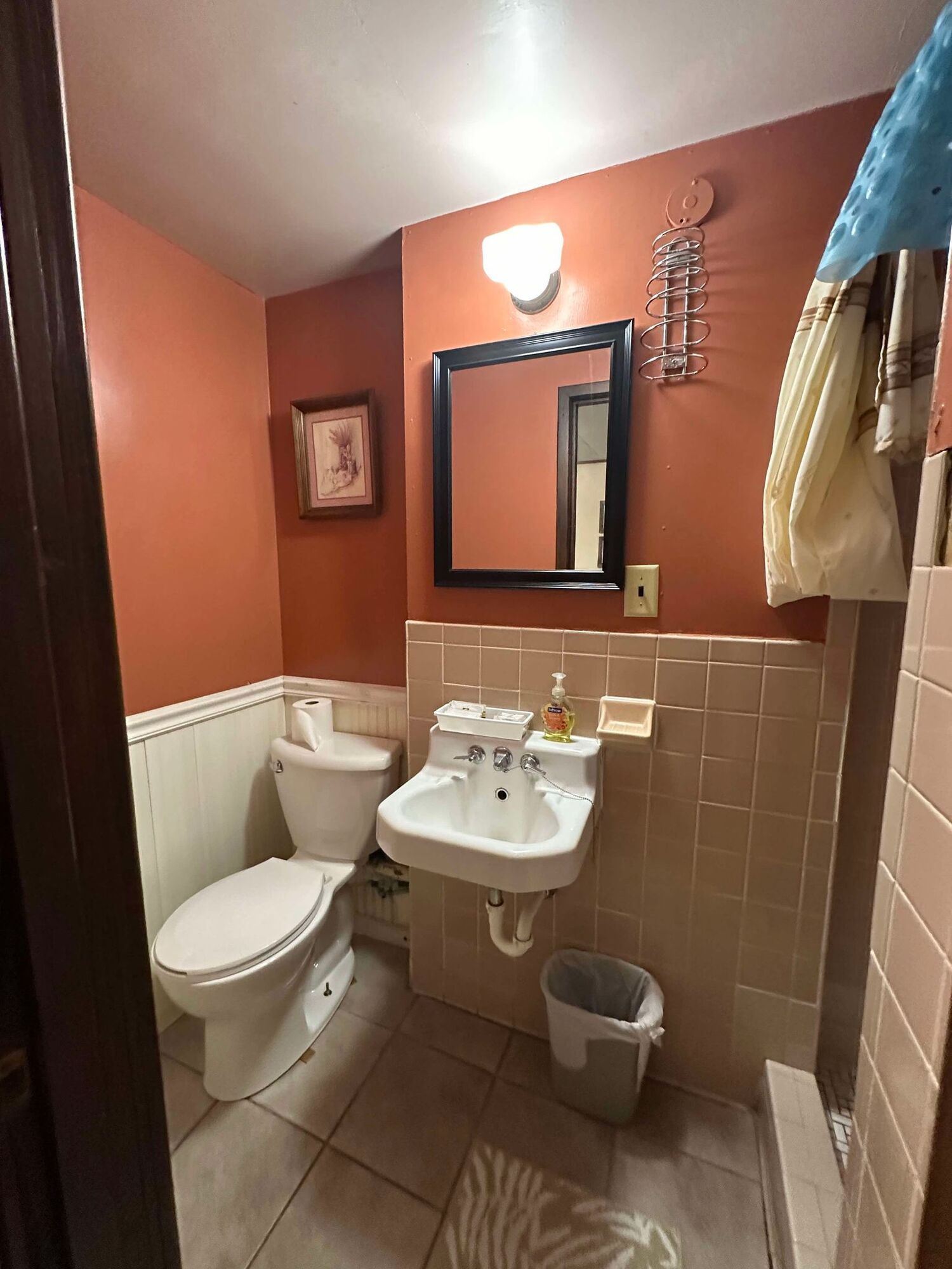 A bathroom with a toilet , sink and mirror.