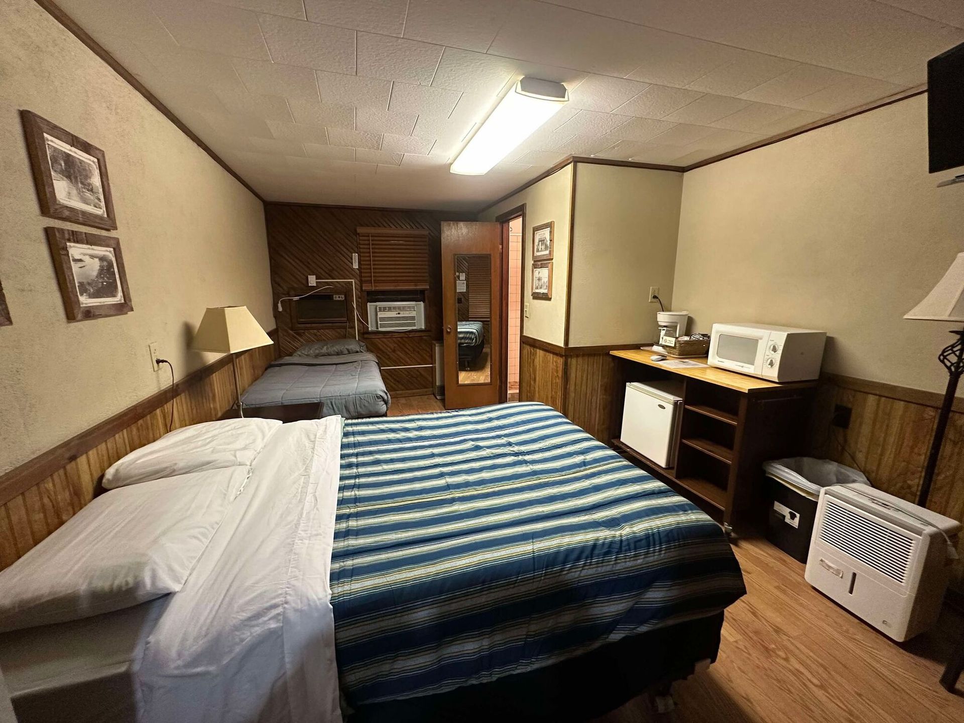 A hotel room with two beds and a microwave.