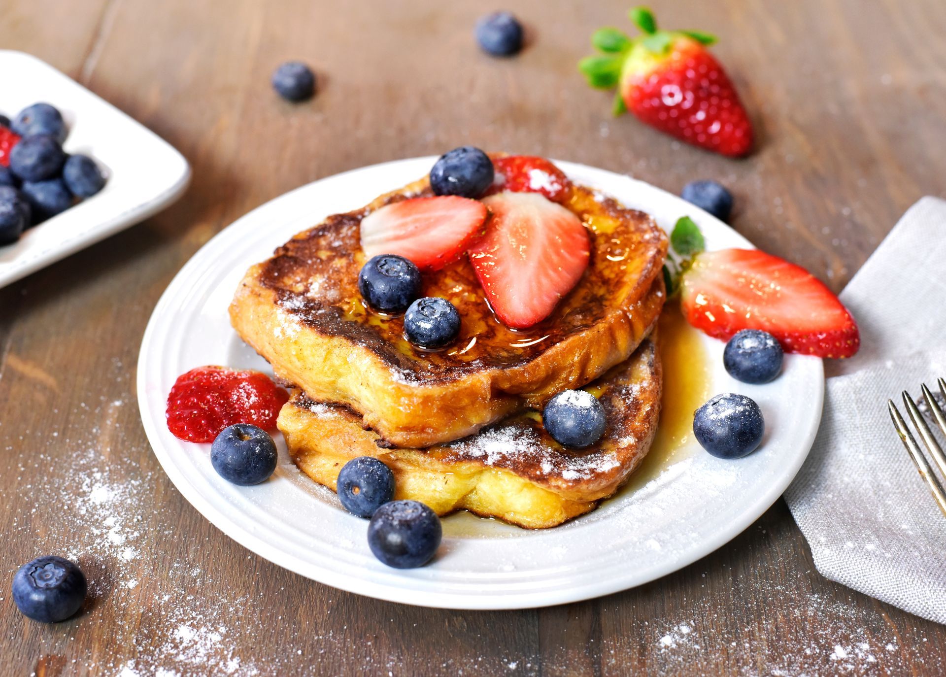 French toast with strawberries and blueberries on a white plate