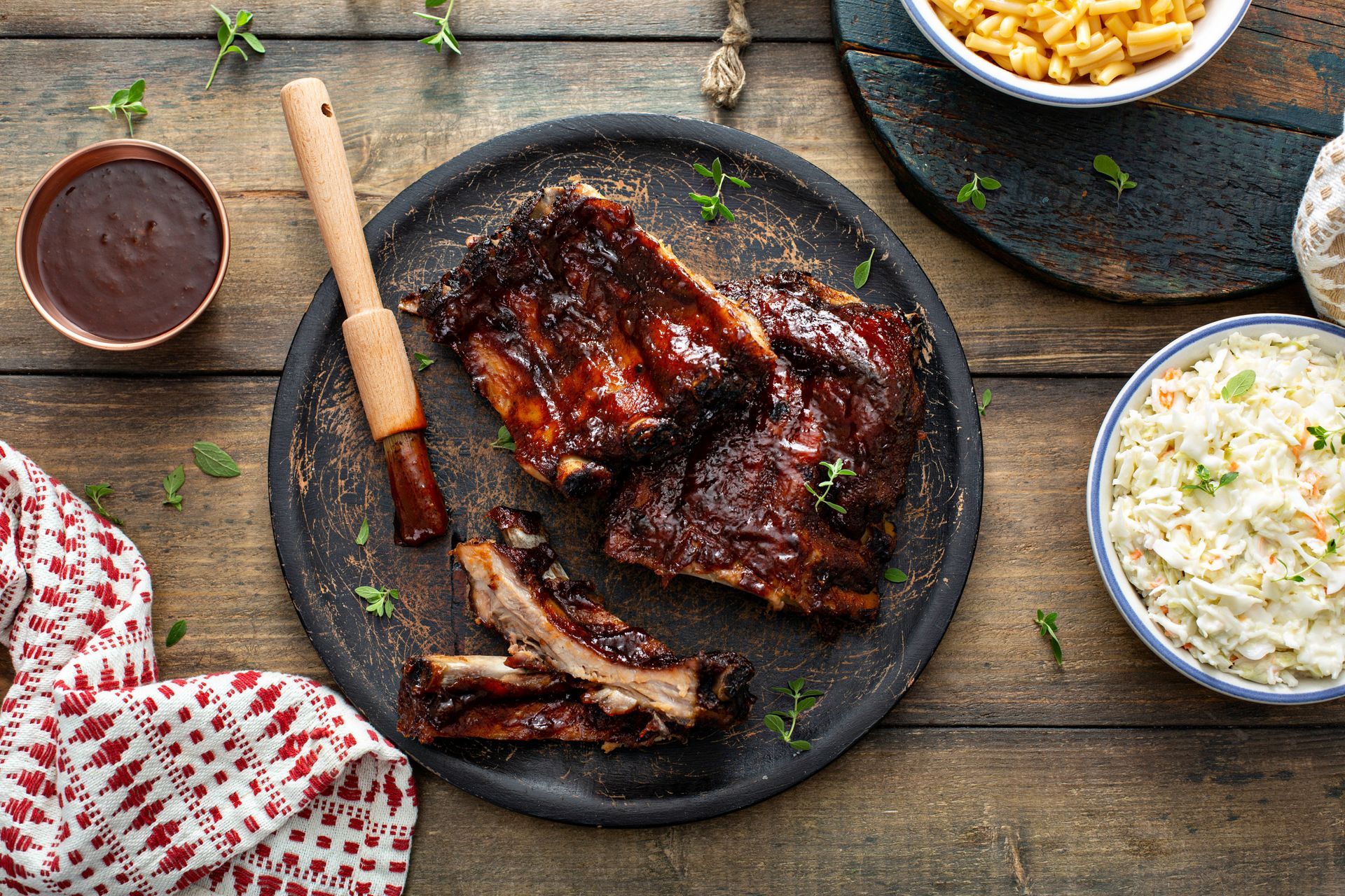 A plate of barbecue ribs with coleslaw and macaroni and cheese on a wooden table.