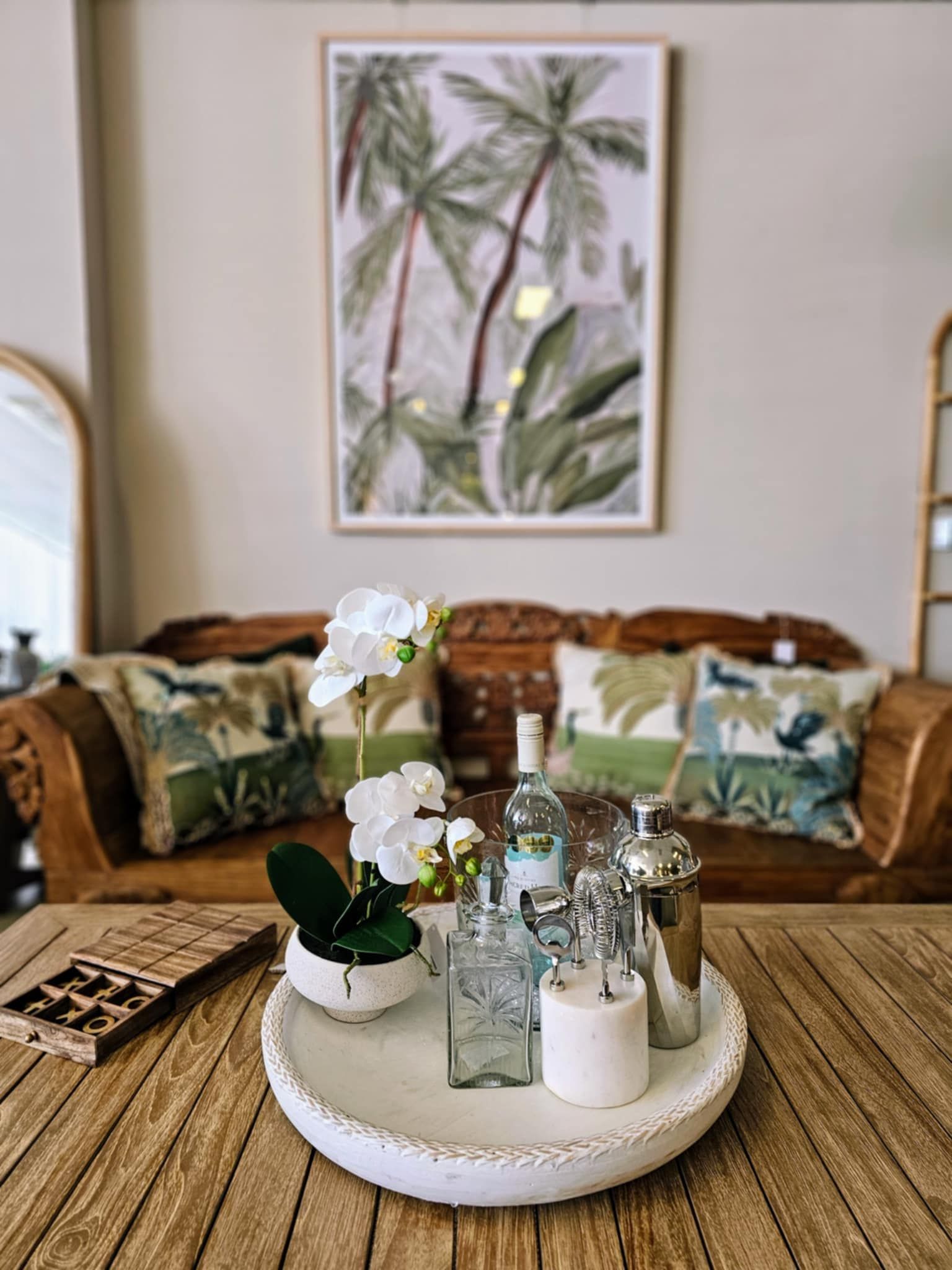 Wooden Table with Decor in Front of A Wood Couch with Pillows and Palm Art  — Tropic Living in Mossman, QLD