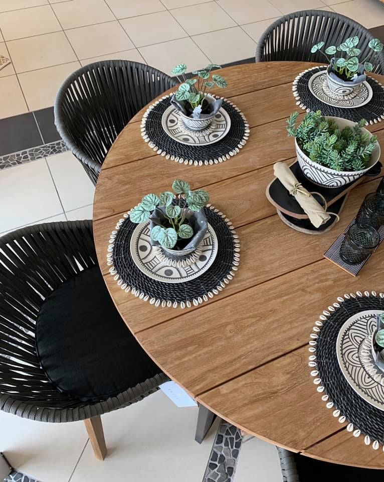 Round Wooden Table with Dishes, Plants, and Four Black Chairs — Tropic Living in Port Douglas, QLD