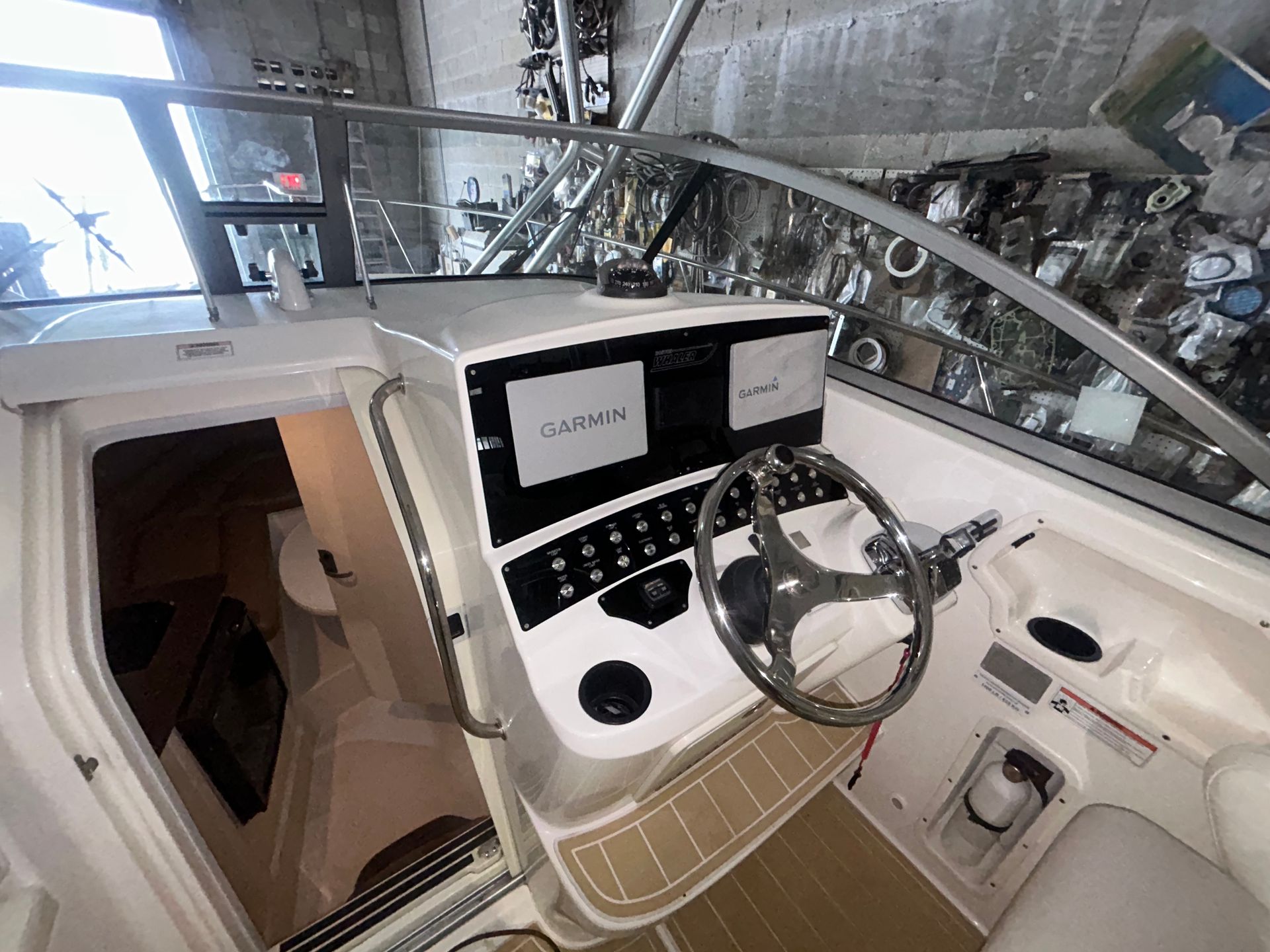 Boat cockpit interior with Garmin displays, steering wheel, and control panel.
