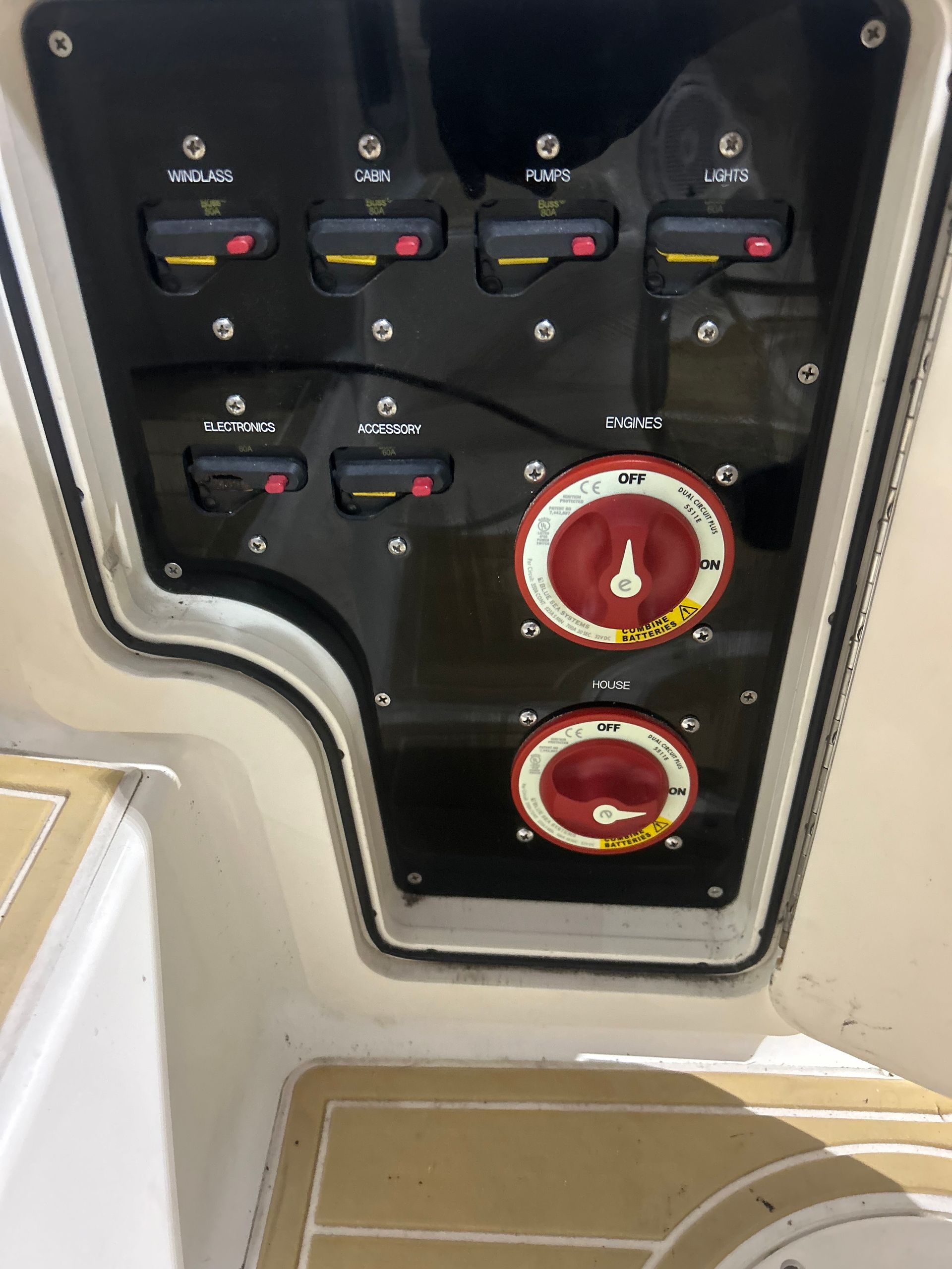 Black boat control panel with switches, gauges, and battery cut-off switches in a white interior.
