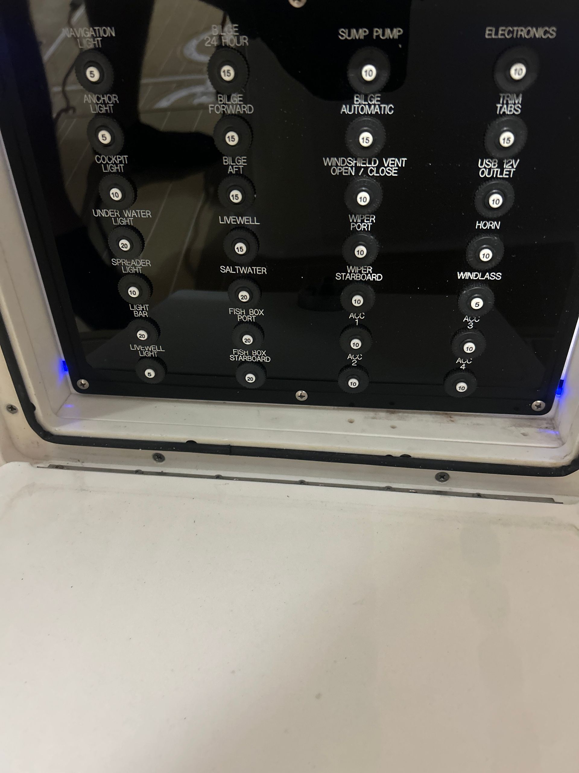 Black boat control panel with labeled switches and blue lights.