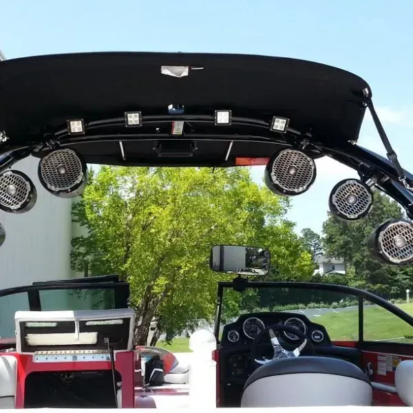Boat interior with speakers, lights, and windshield. Black roll bar, red accents.
