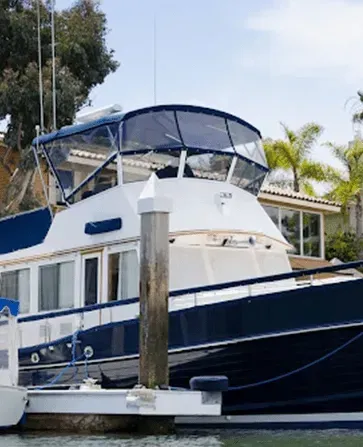 A navy and white boat docked at a pier, with a clear covered upper deck.