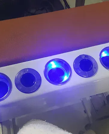 A foot soaking station with blue lights shining in the bowls.