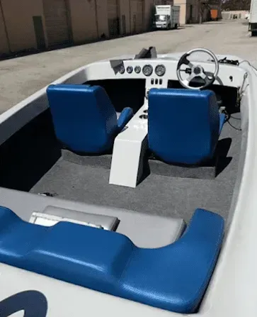 Blue and white motorboat interior with seats, steering wheel, and dashboard.