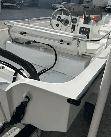 White motorboat on a trailer, cockpit with steering wheel and controls, exterior view.