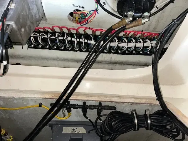 Electrical wiring and components on a boat, including black cables, wires, and connectors.