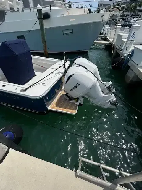 A small blue and white boat with two white Yamaha engines docked in a marina.