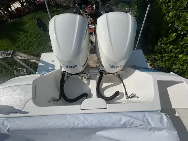 Two white outboard boat motors on the stern of a white boat; setting is outdoors on the water.