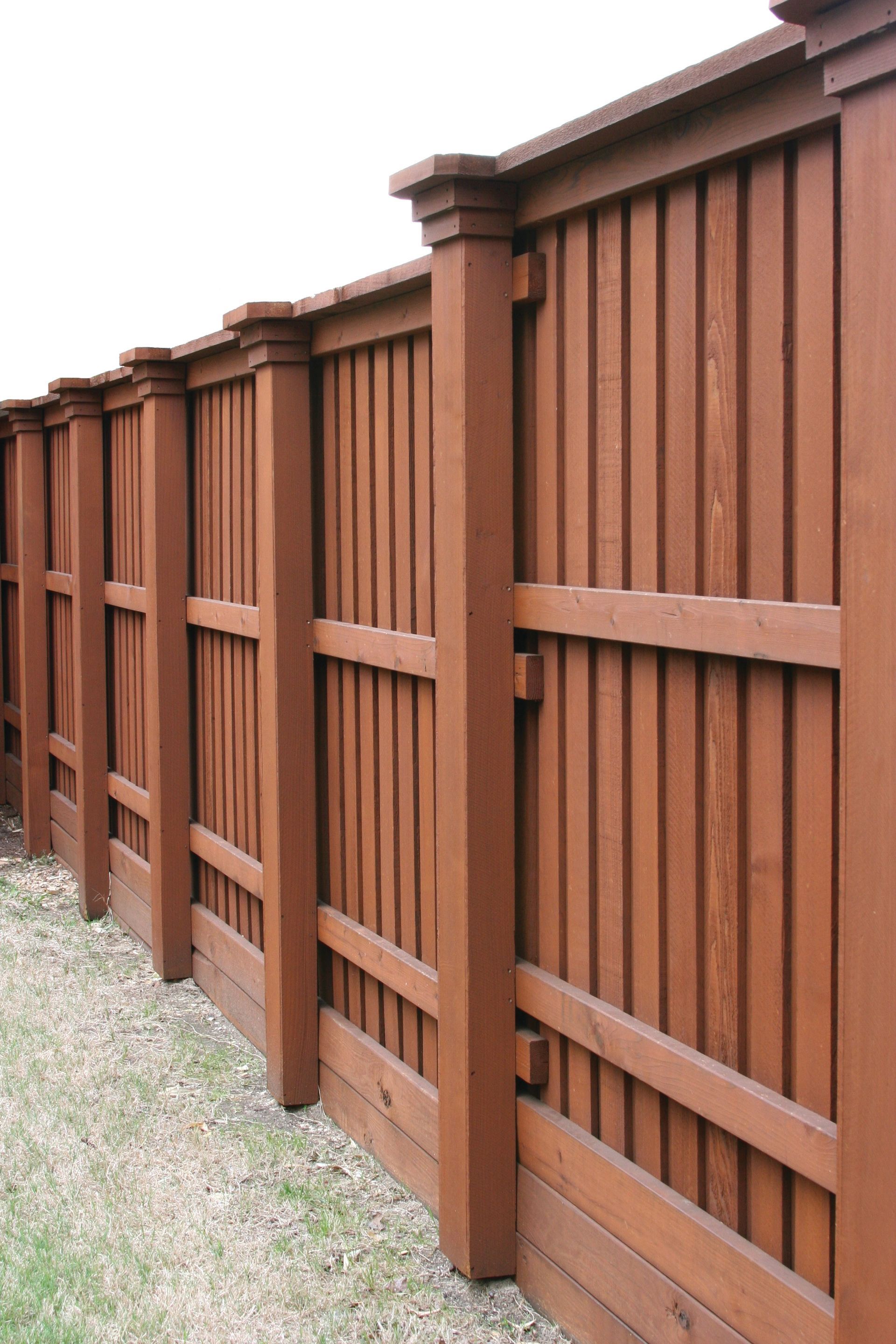 Brown wooden fence with vertical slats and decorative posts.