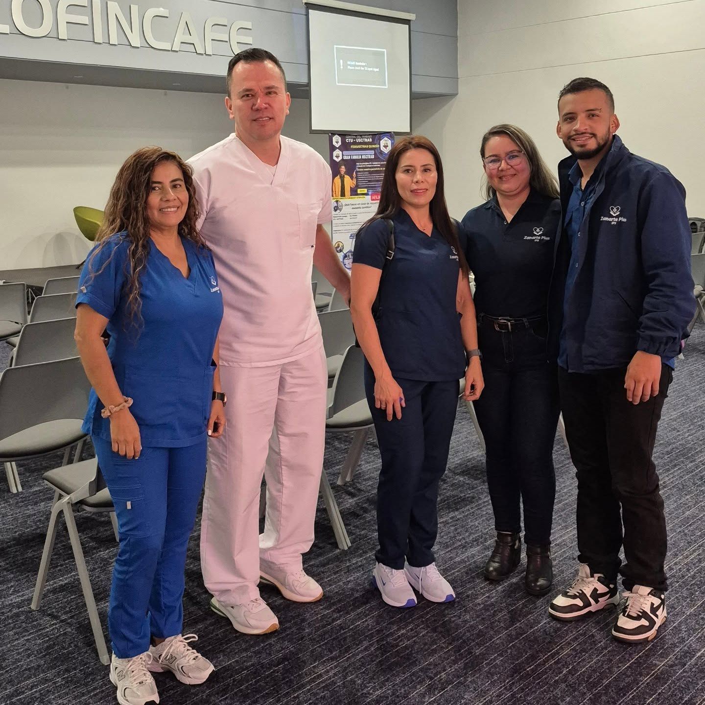 Grupo de cinco personas en una habitación, algunas con batas médicas.