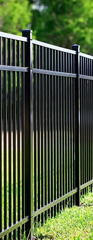 A black metal fence is sitting in the middle of a lush green field.