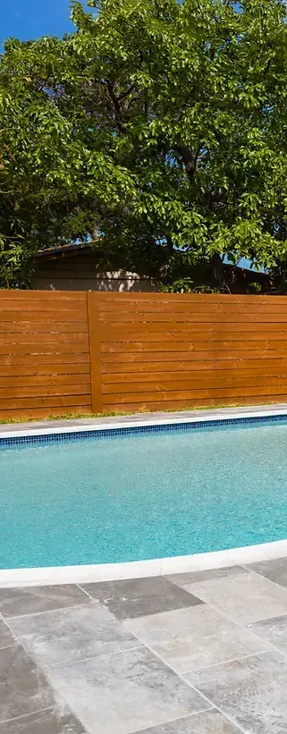 A large swimming pool with a wooden fence surrounding it.