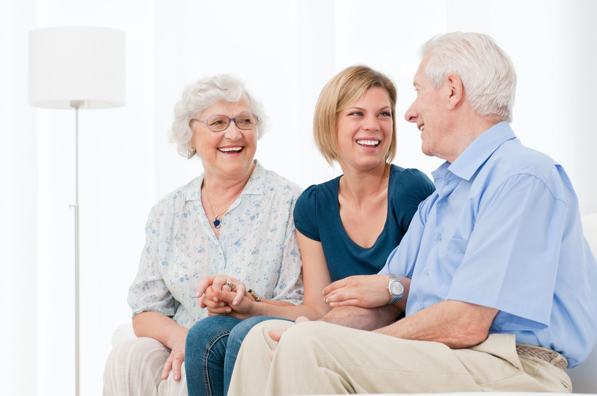 A man and two women are sitting on a couch talking to each other.