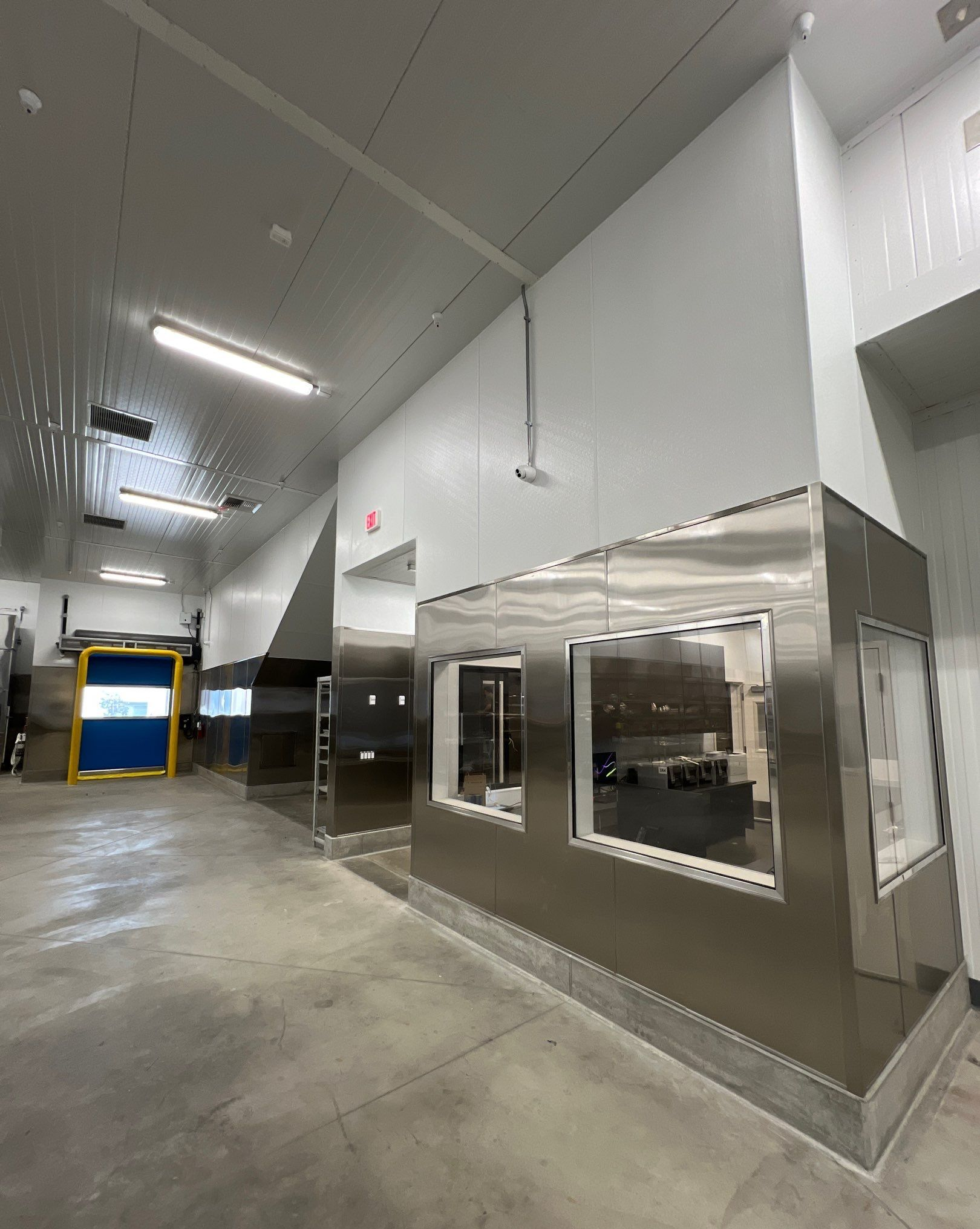 Interior of a stainless steel commercial building with windows and a loading door.