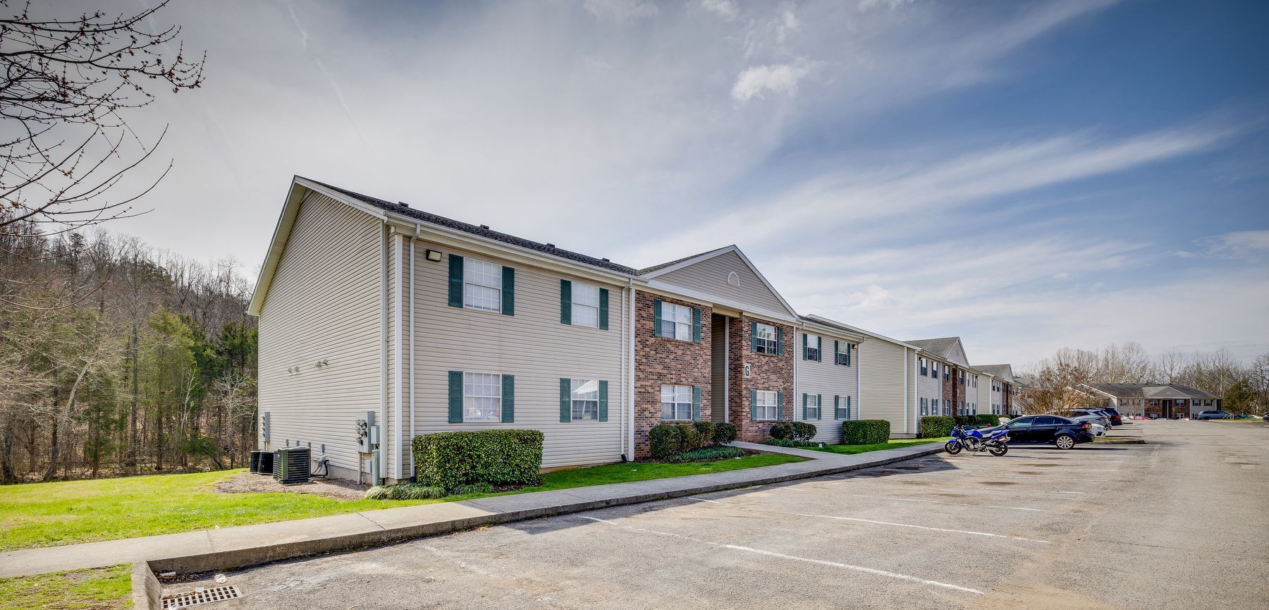 A large apartment building with a parking lot in front of it.