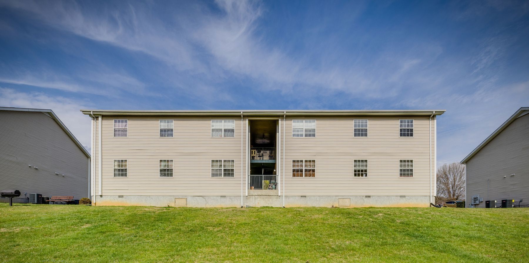 A large apartment building is sitting on top of a lush green hill.