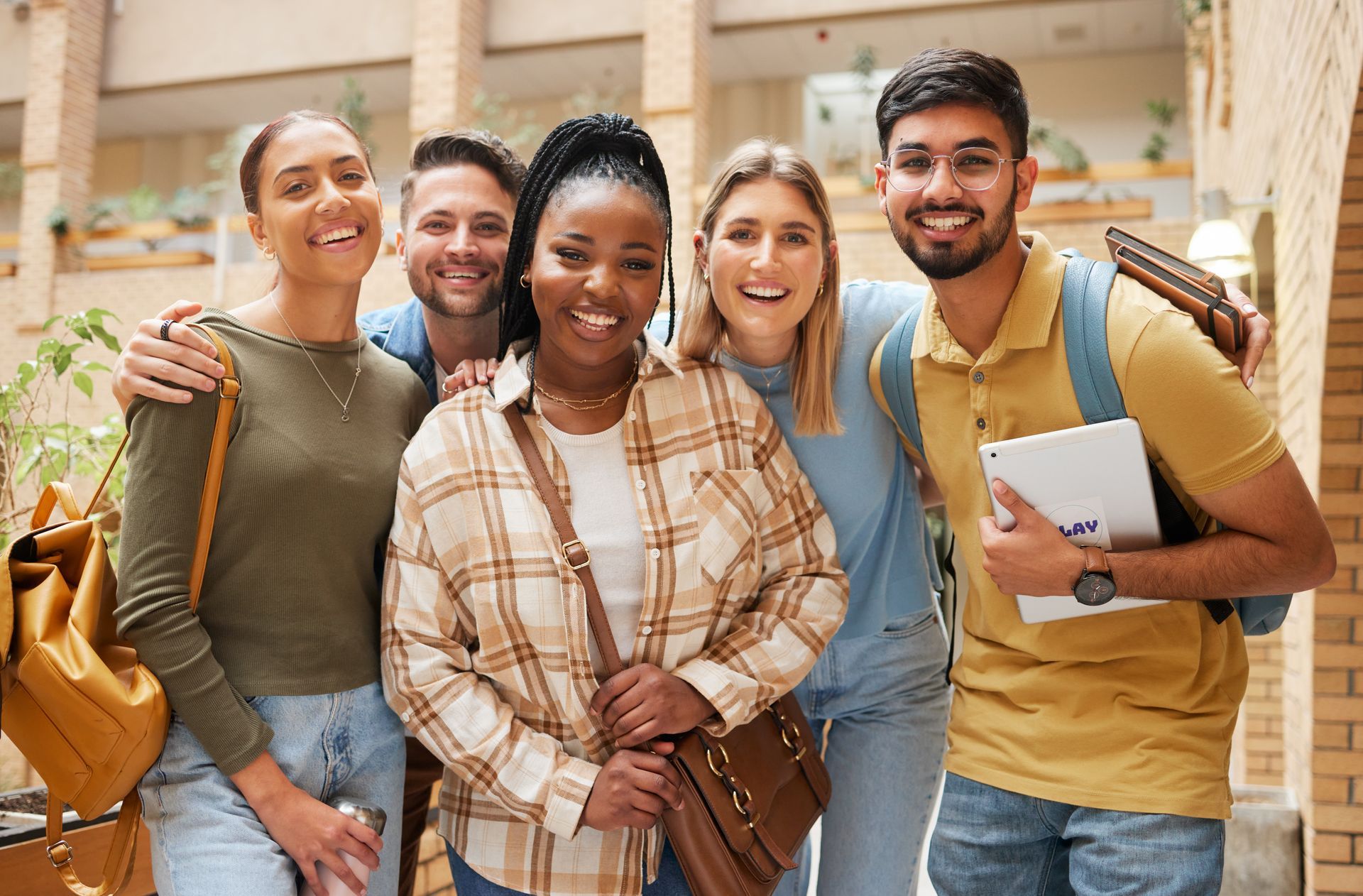Group of students smiling, posing for a photo in a brick-walled university building. Group of students smiling, posing for a photo in a brick-walled university building.