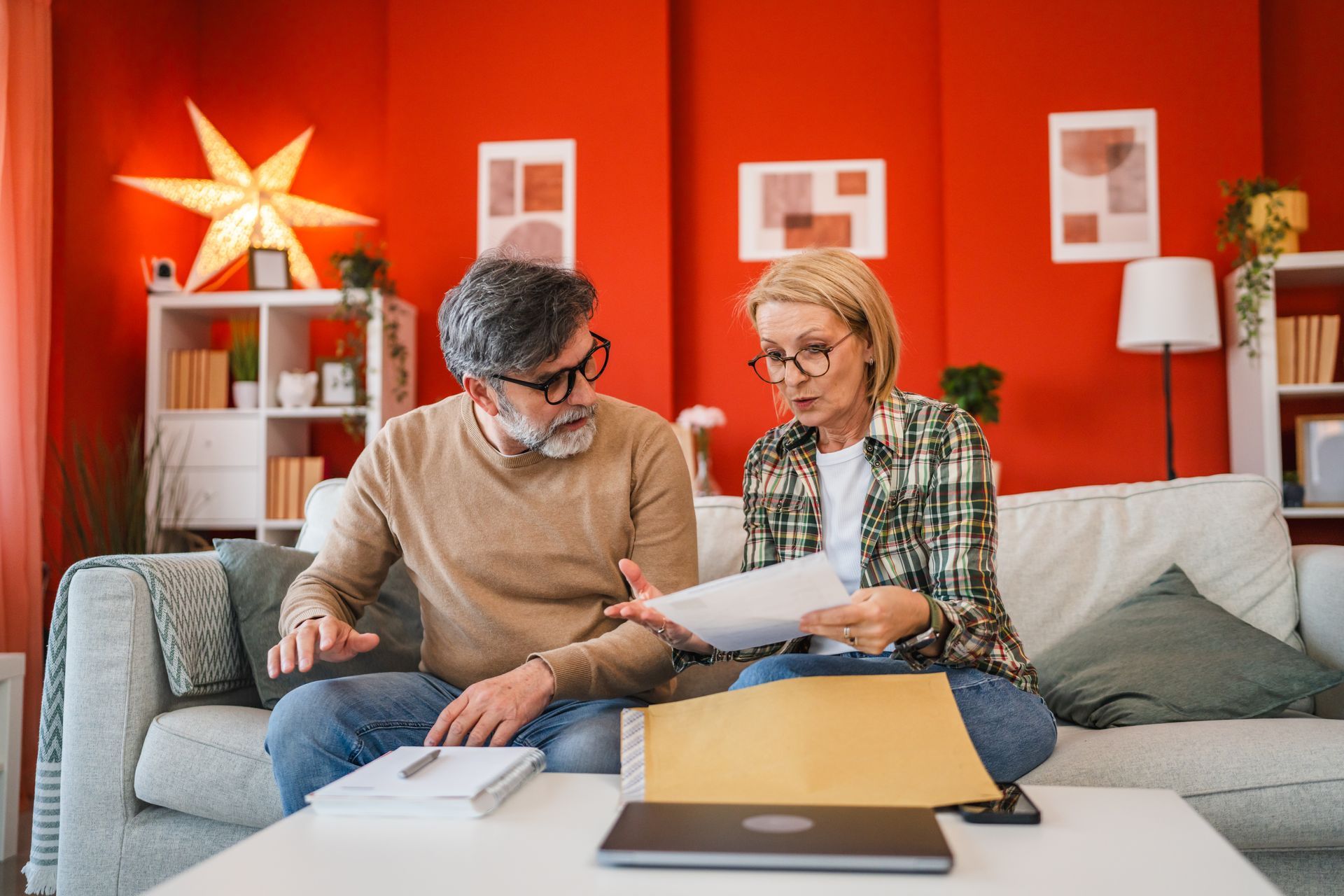 A man and a woman are sitting on a couch looking at papers.