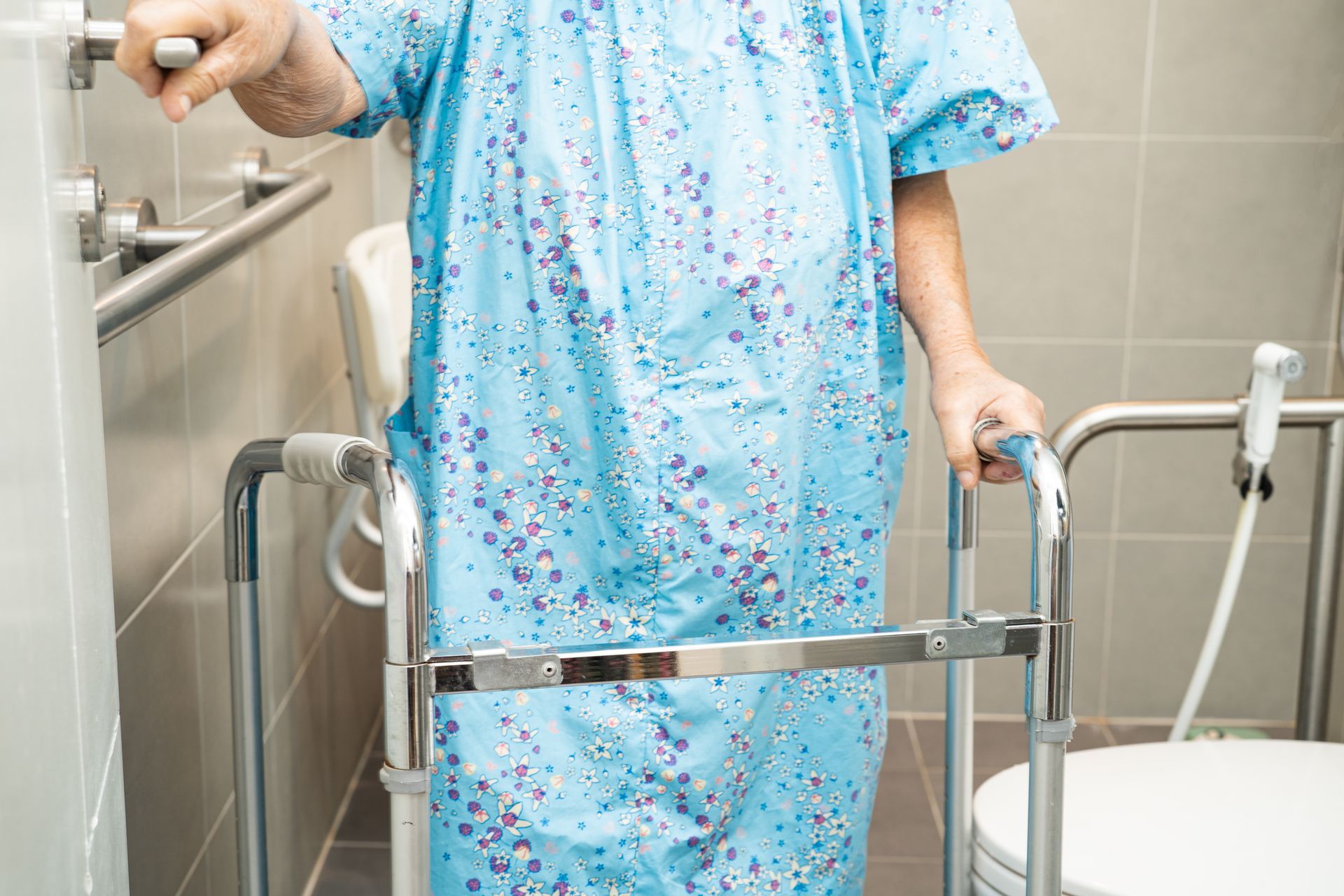 An elderly woman is using a walker in a bathroom.