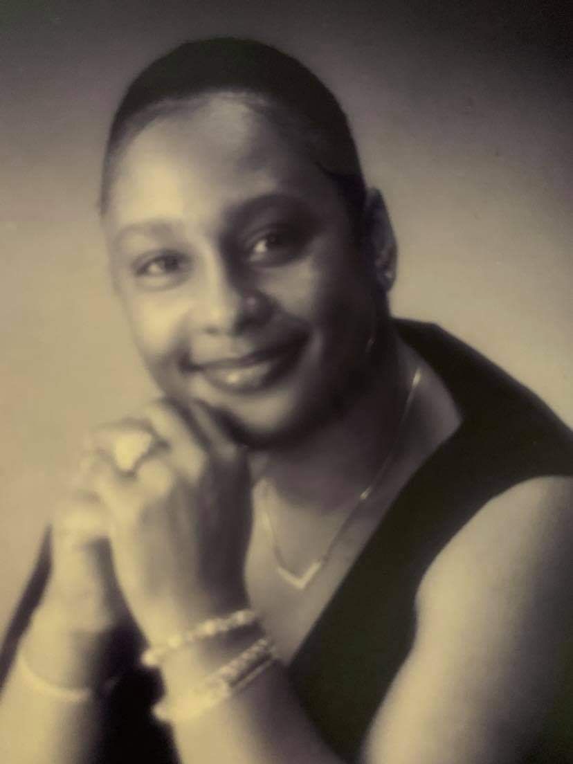 A black and white photo of a woman with her hand on her chin.
