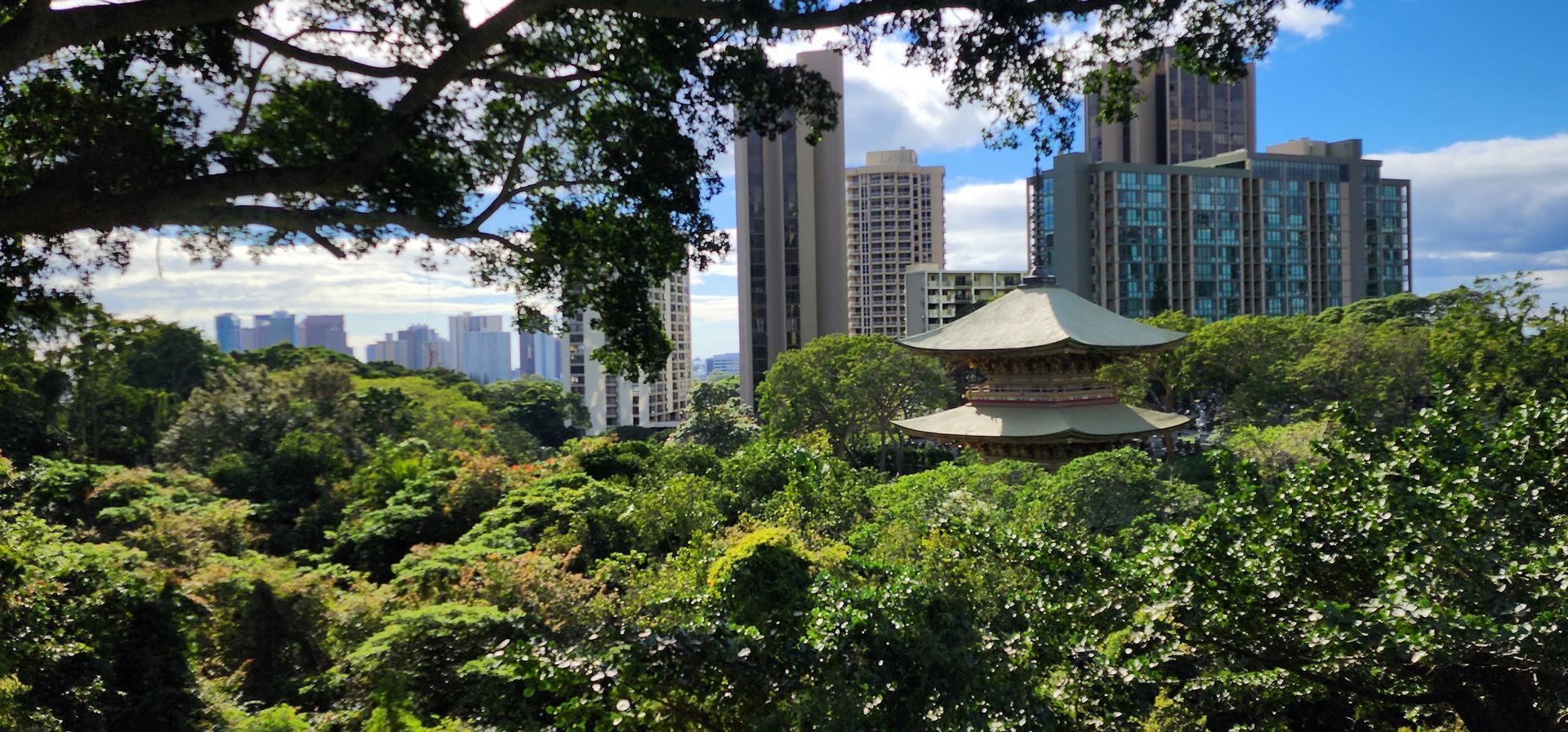 A view of a city through trees with a pagoda in the foreground