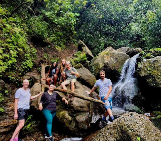 A group of people are posing for a picture in front of a waterfall.
