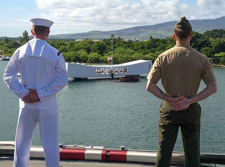 Sailor and Marine in uniform overlooking the USS Arizona Memorial in Pearl Harbor.