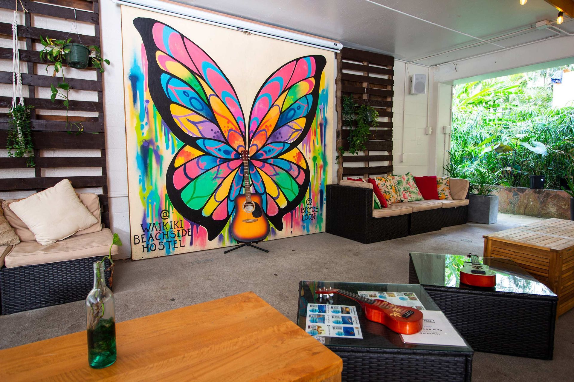A vibrant outdoor seating area with a butterfly mural and acoustic guitar.