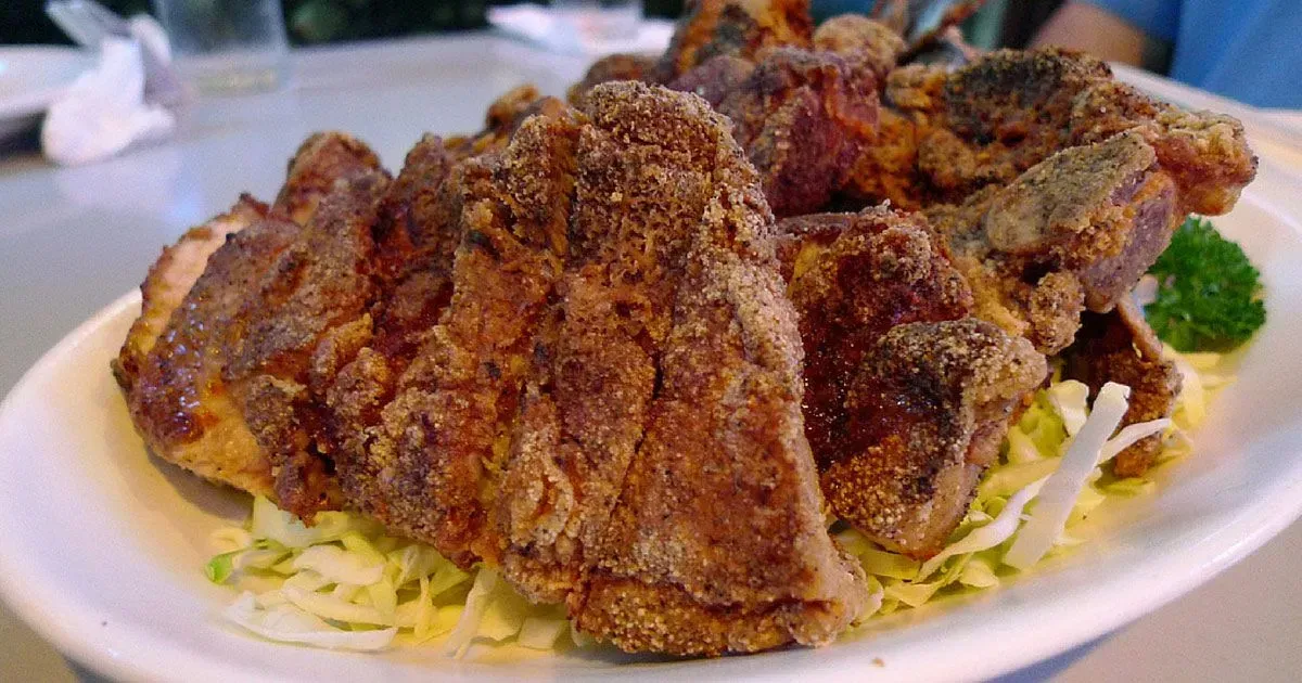 A white plate topped with fried meat and cabbage on a table.