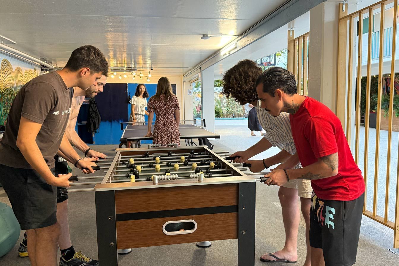 A group of young men are playing foosball in a room.