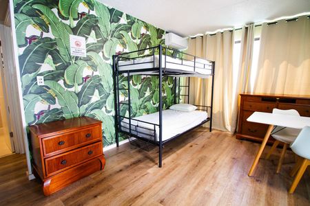 A bedroom with a bunk bed , dresser , desk and chairs.