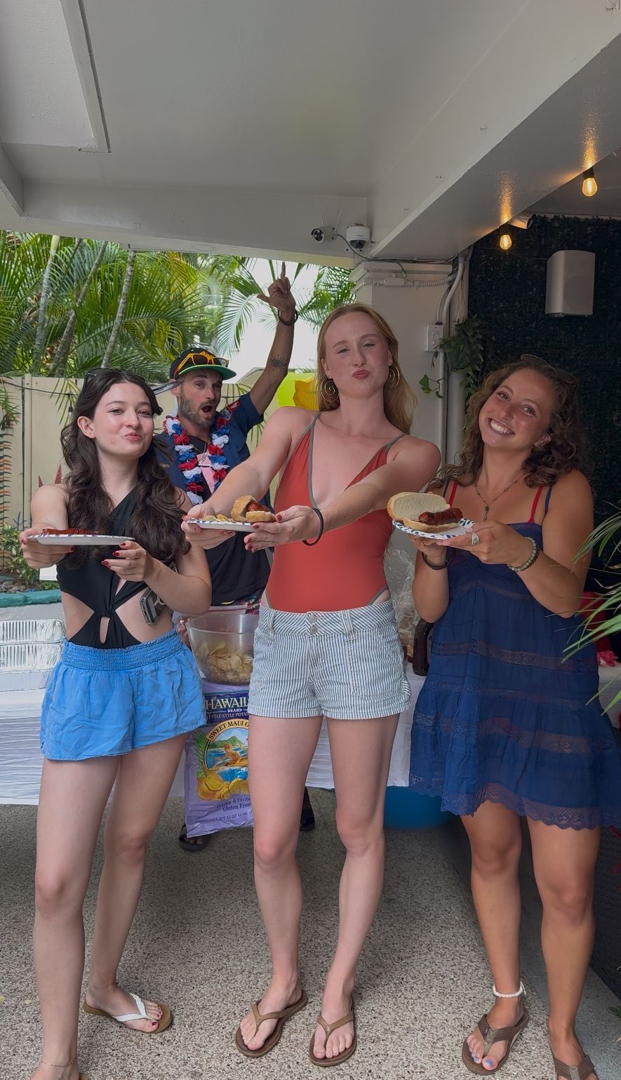 Three women are standing next to each other holding plates of food.