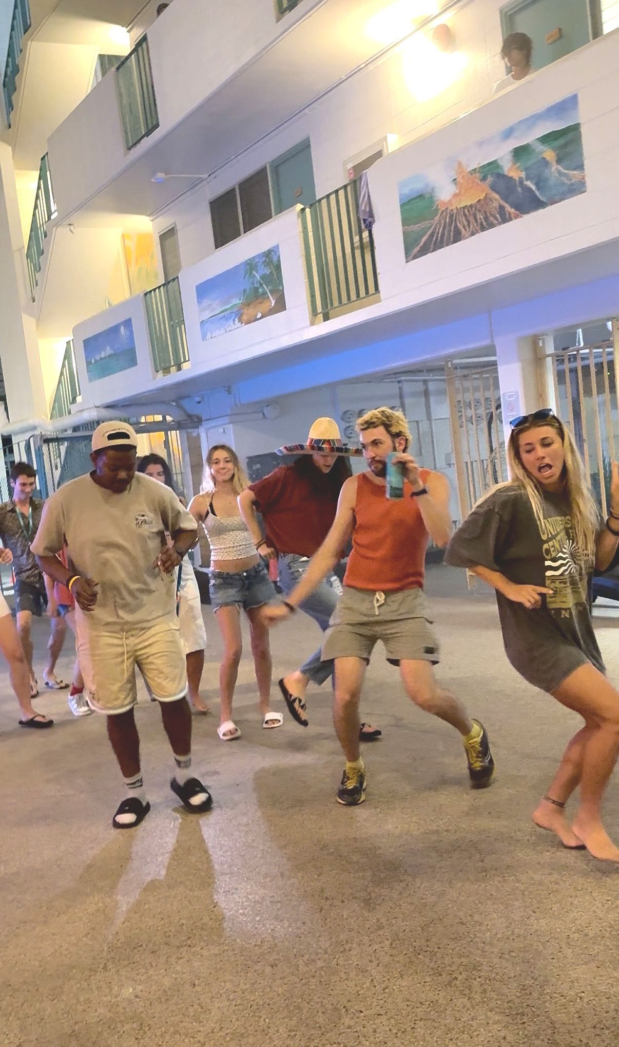 People dancing in a well-lit outdoor area. A diverse group, with varied expressions, moves to the music.