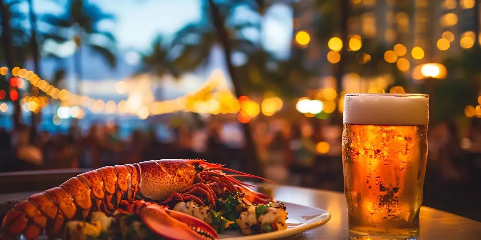 A plate of lobster and a glass of beer on a table.