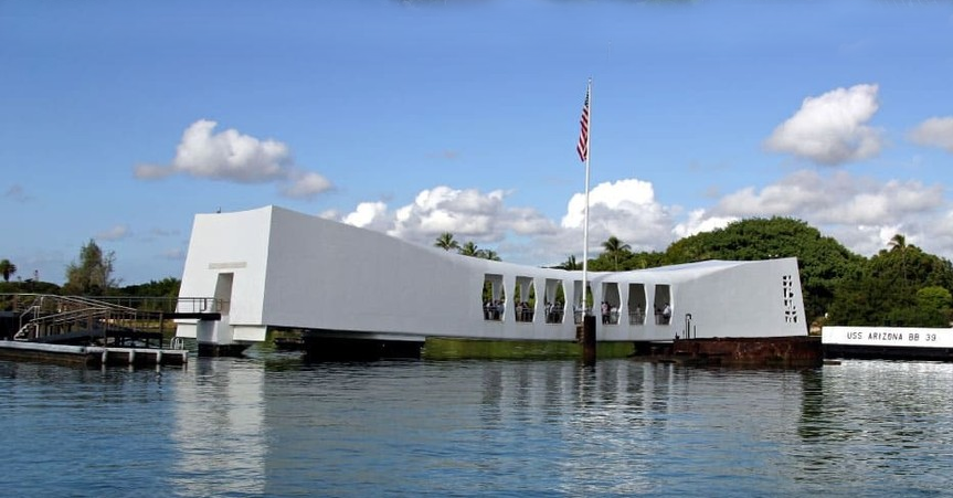 Pearl Harbor Memorial, white structure over water with US flag, honoring those lost during the attack.