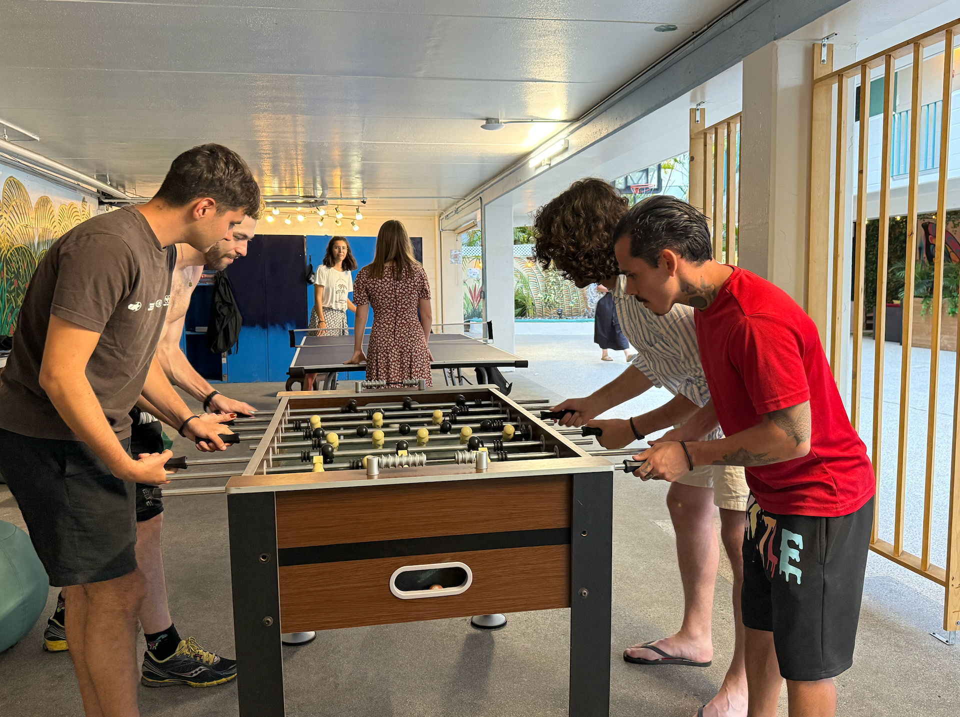 A group of young men are playing foosball in a room.