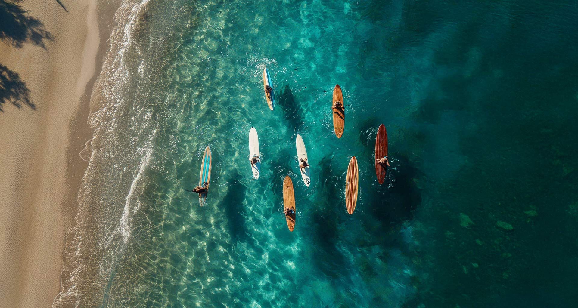 An aerial view of people paddleboarding on clear blue water near a sandy beach.