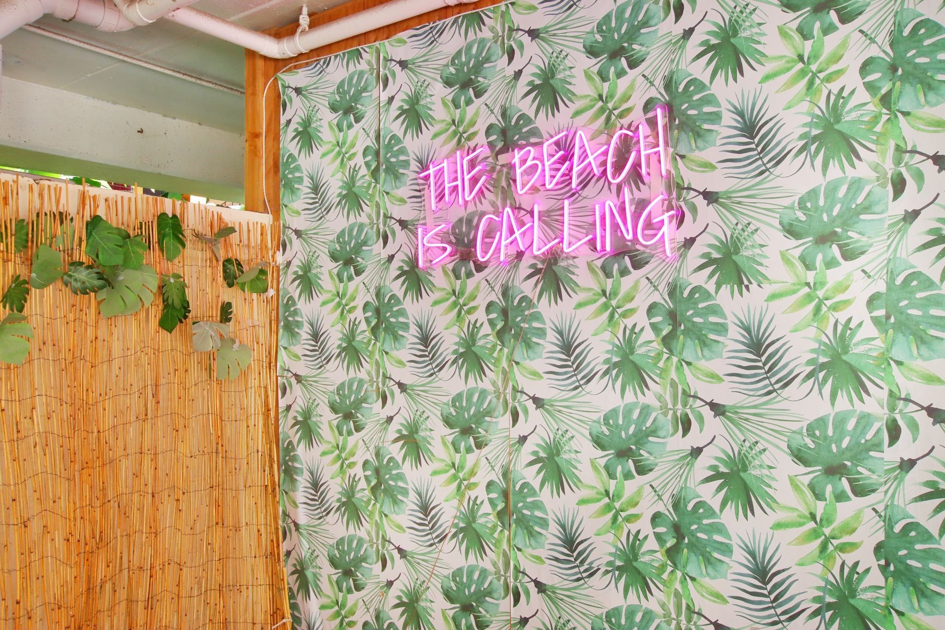 There is a neon sign on the wall that says `` the beach is calling ''.