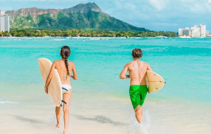 A man and a woman are walking on the beach holding surfboards.