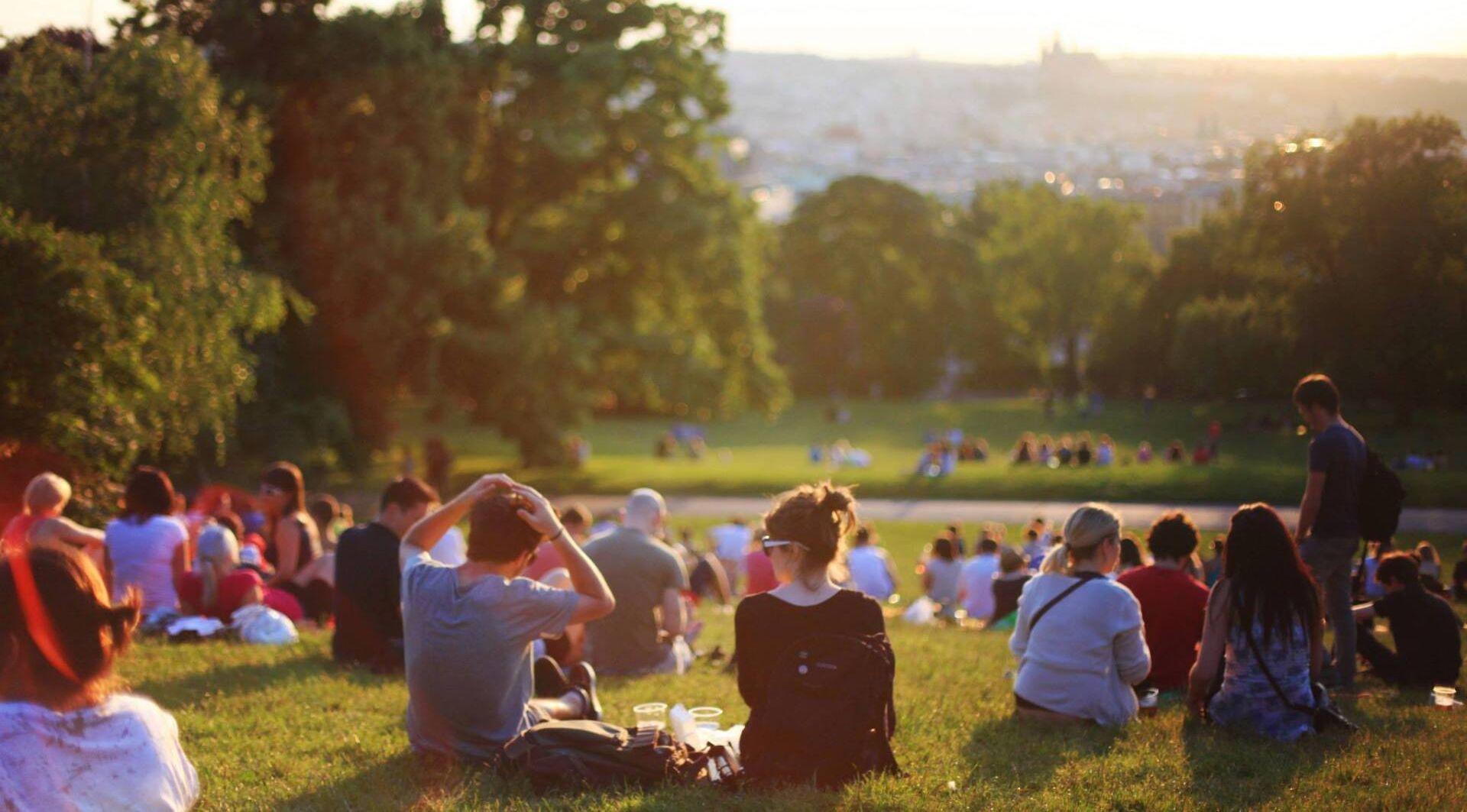 A group of people are sitting on the grass in a park.