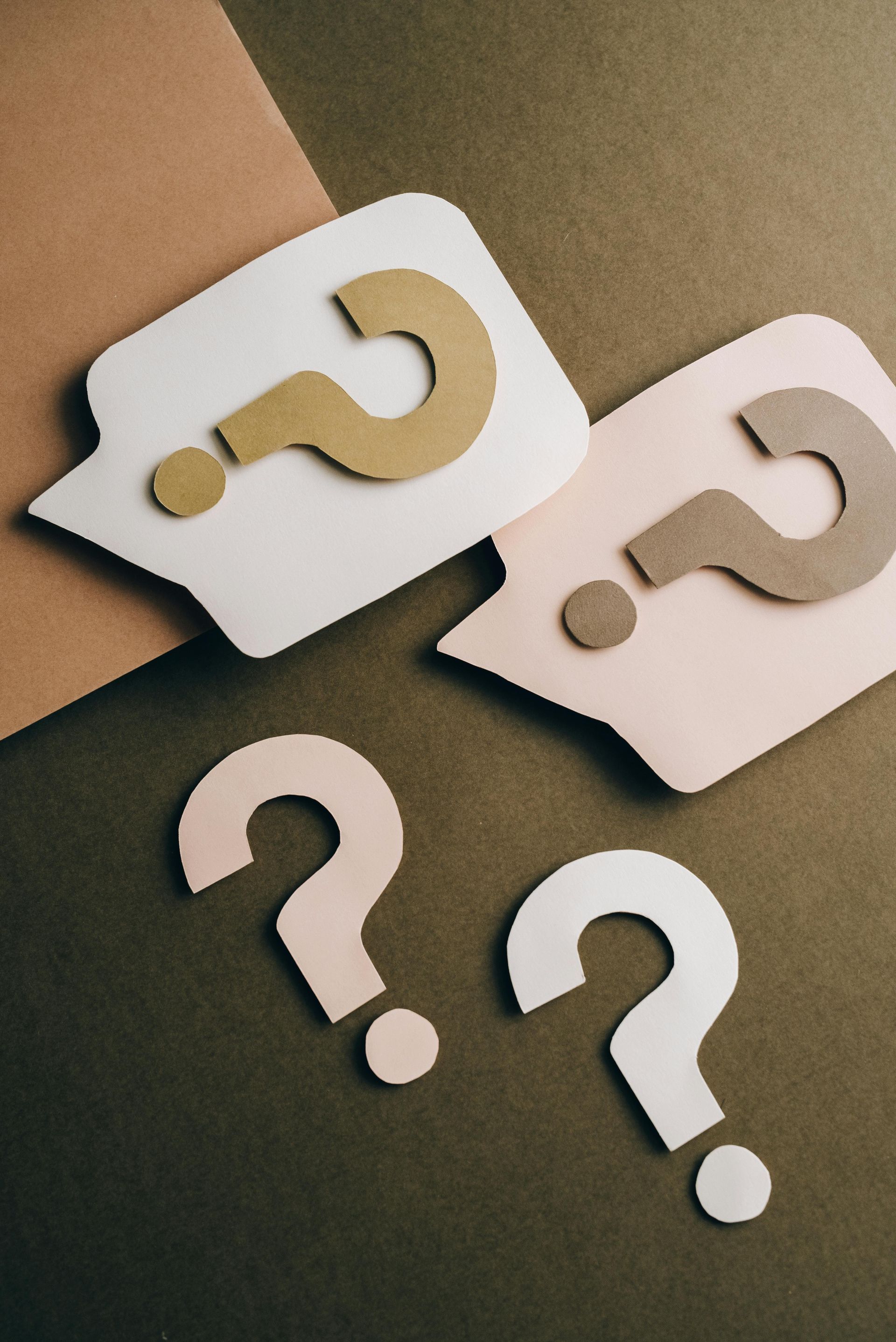 Two speech bubbles with question marks cut out of them