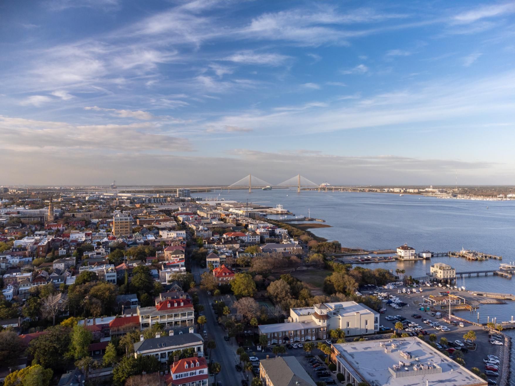 Charleston, South Carolina, cityscape with waterfront and Arthur Ravenel Jr. Bridge under a blue sky.