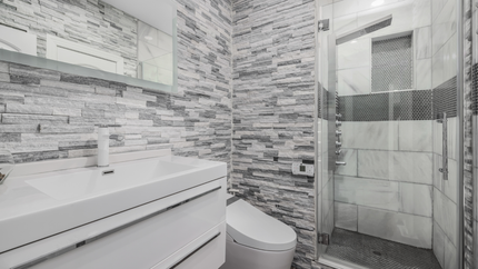 A bathroom with a toilet , sink , mirror and walk in shower.