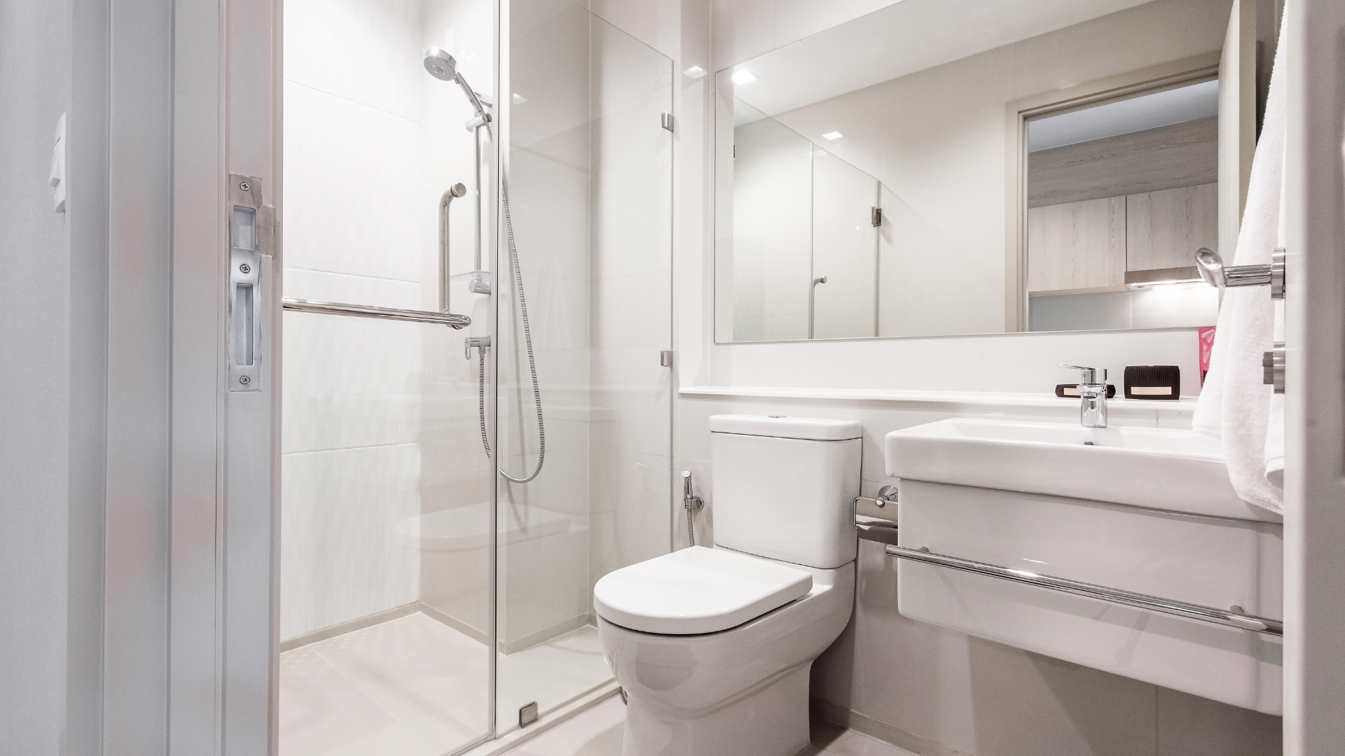 A bathroom with a toilet , sink , shower and mirror.