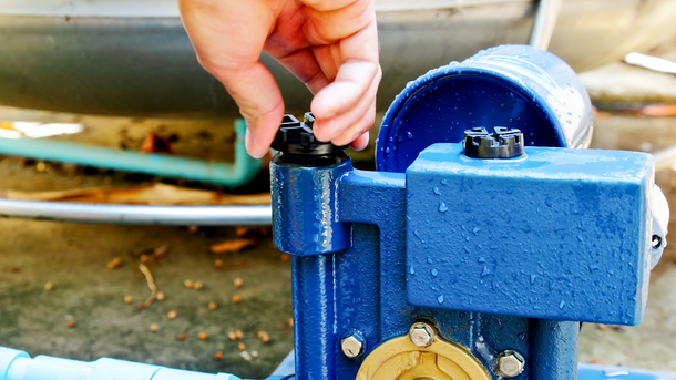 A person is fixing a water pump with their hand.